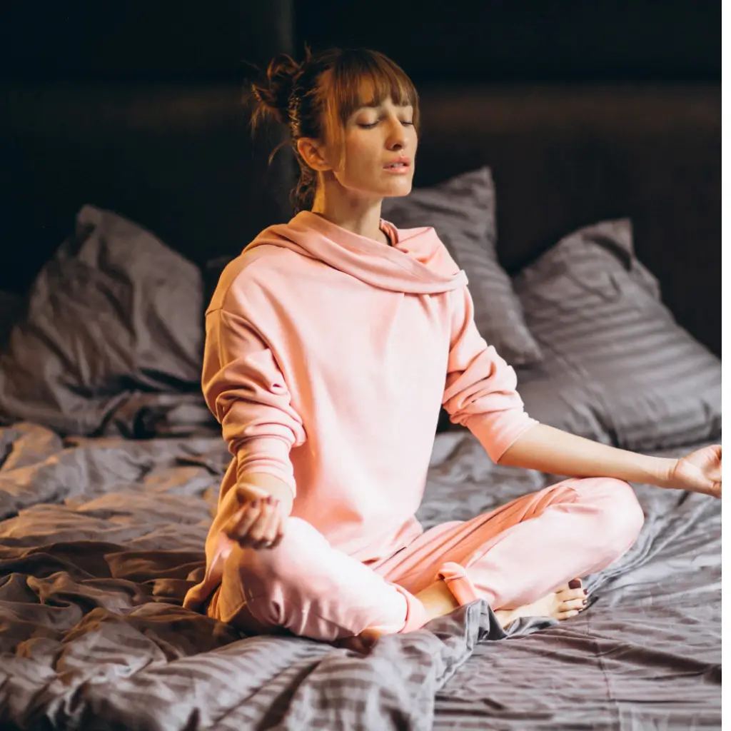 Woman practicing deep breathing and meditation before bed to help sleep with tinnitus